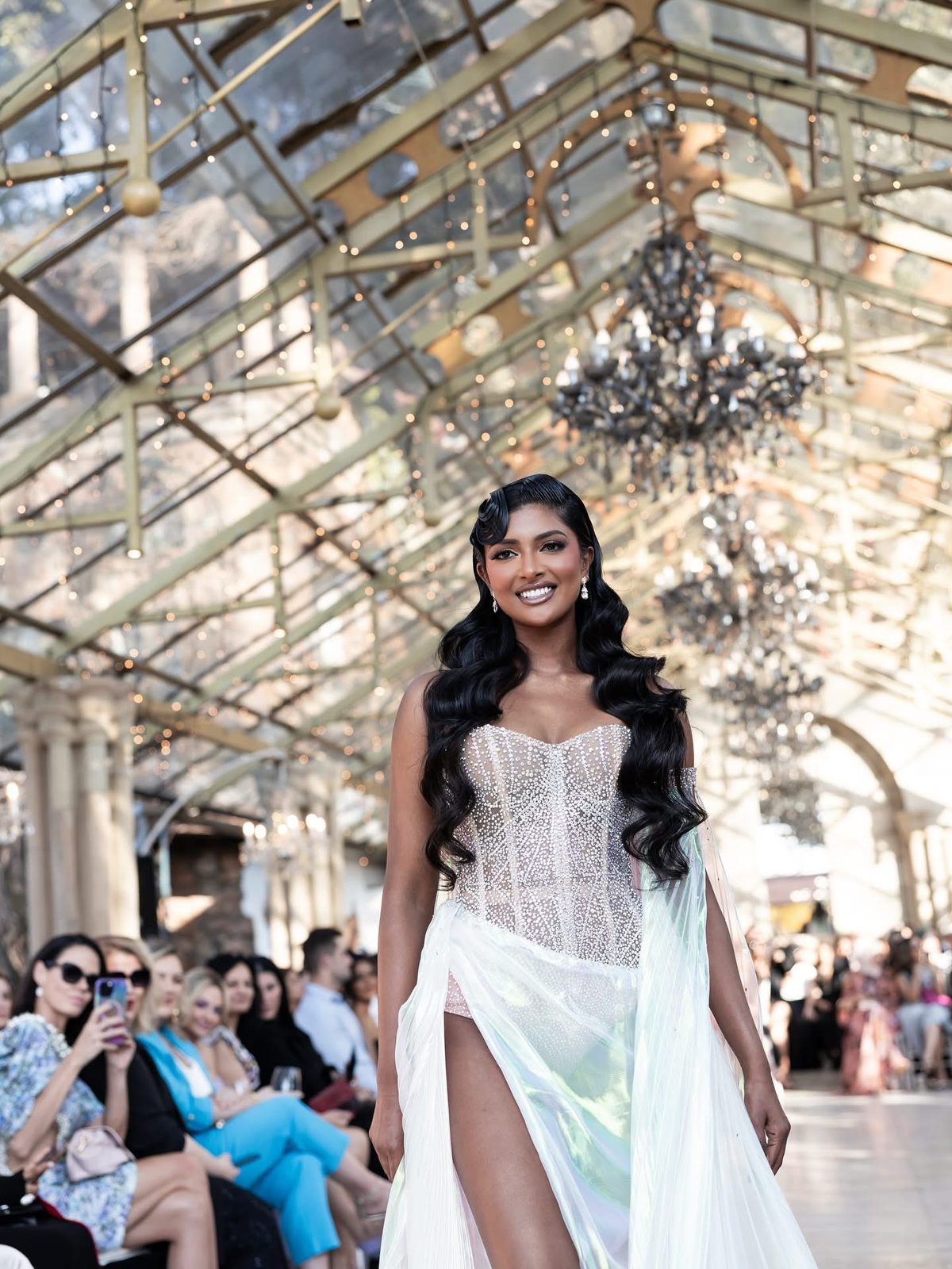 Runway model with waved dark hair in beaded gown