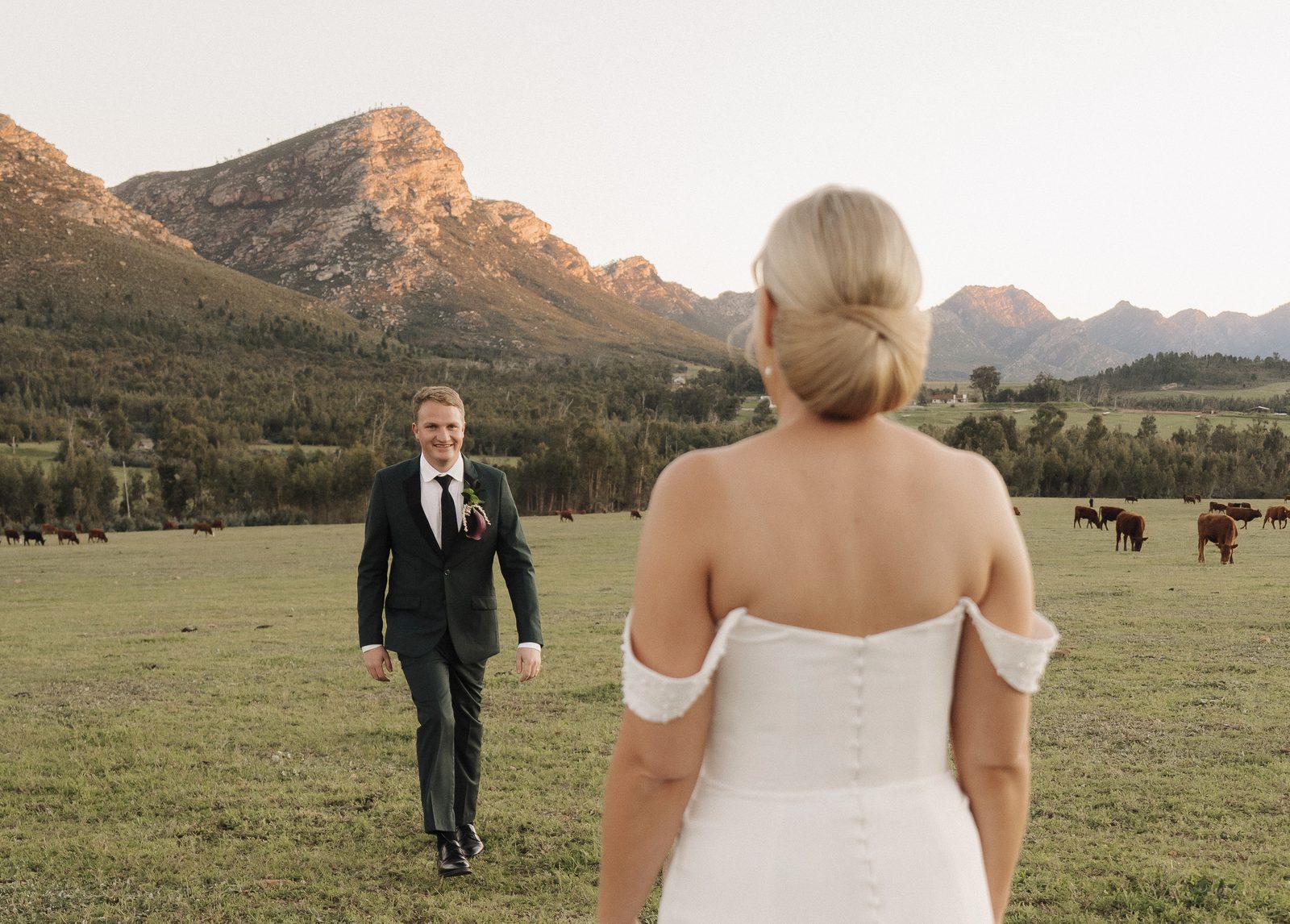 Bride walking toward groom in mountain field