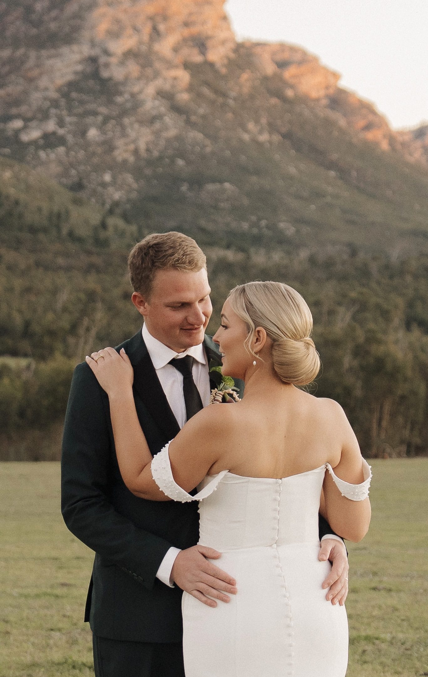 Bride and groom embracing at sunset, styled updo